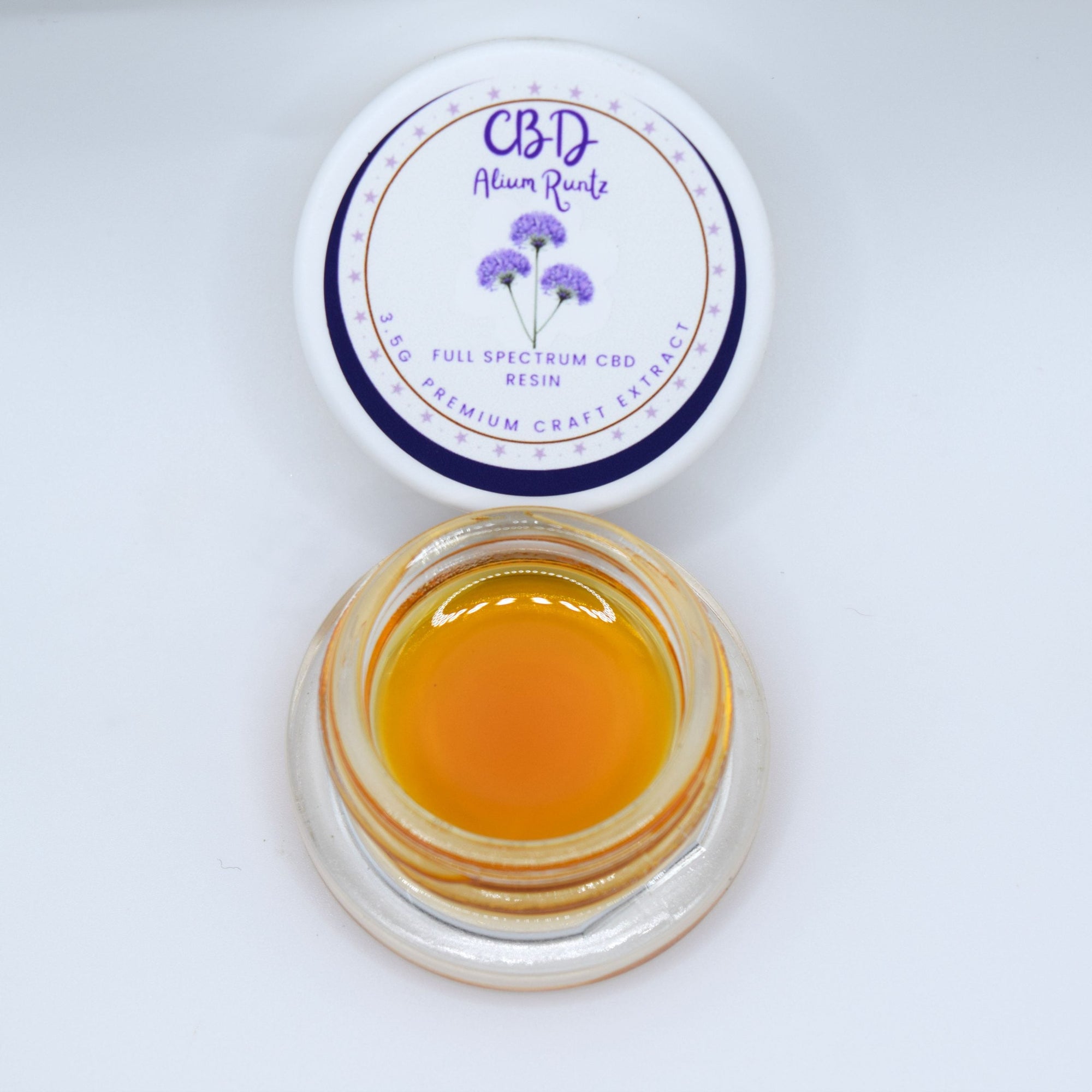 Alium Kush CBD full spectrum extract with glossy golden amber resin and a sweet fruit, savory herb, earthy Kush, spice, wood, and gassy profile.