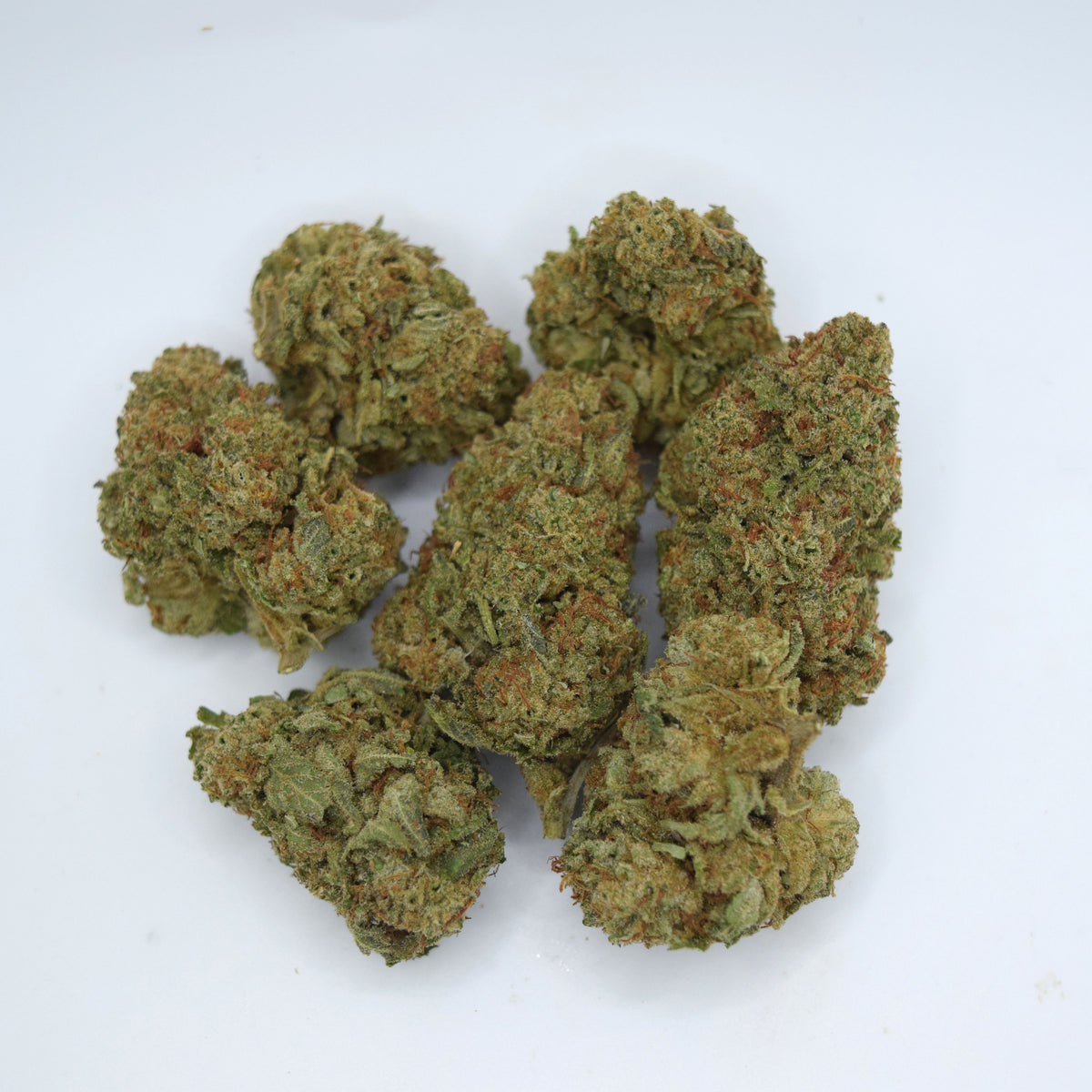 Several dried cannabis buds clustered together on a plain white background.