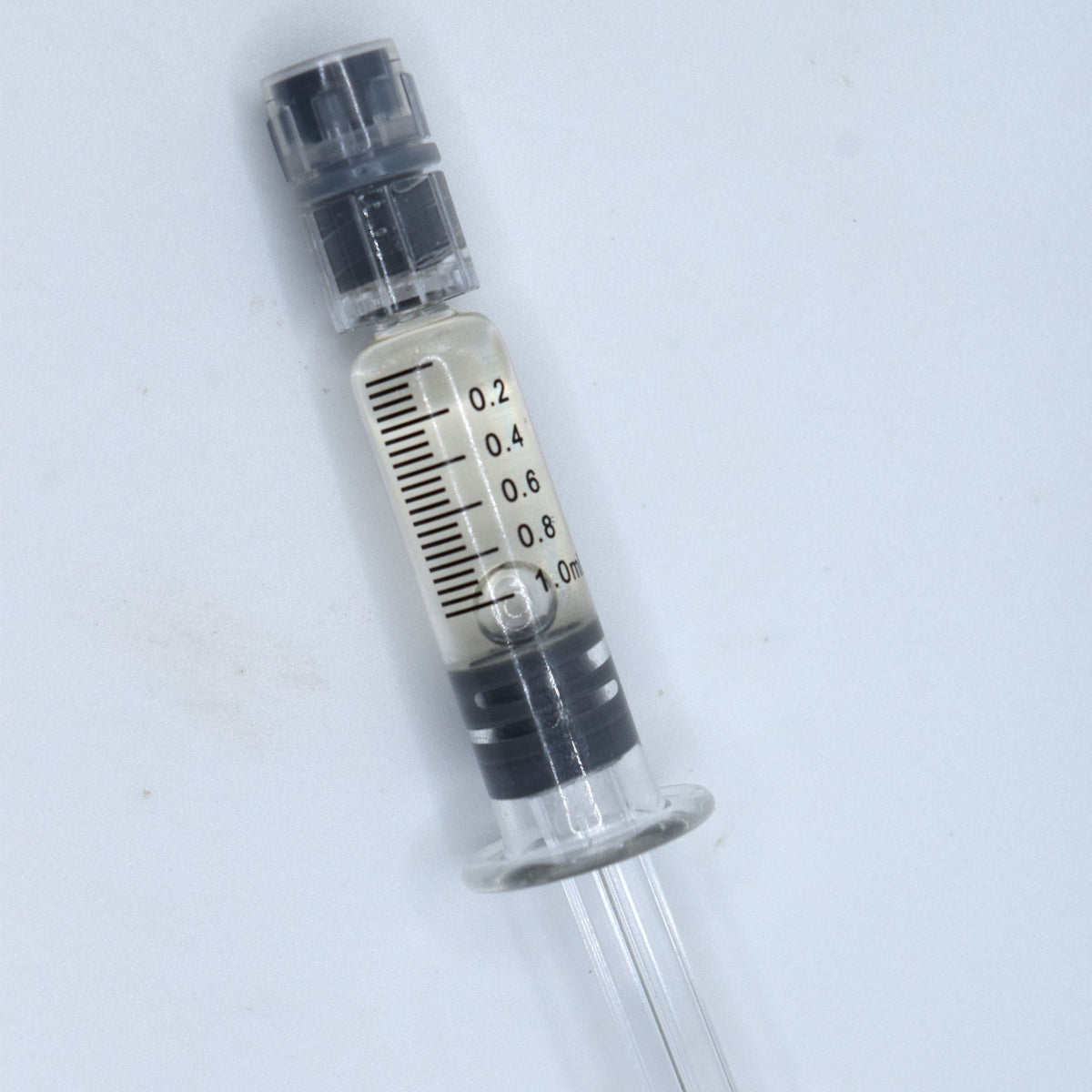 A small CBC filled clear plastic syringe-style tube with black measurement markings and a black cap, shown on a plain light background.