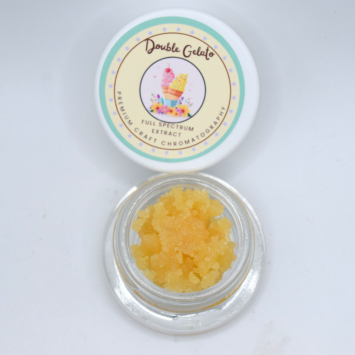 A small clear round jar filled with yellow-orange gel crystals sits below its white lid, which has a colorful label reading 'Double Gelato' and 'Full Spectrum Extract'.