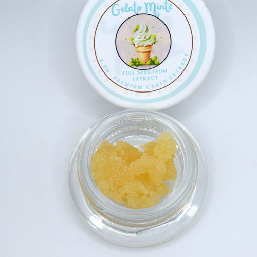 A small clear glass jar filled with translucent yellow gel crystals sits below its matching white lid, which features a mint green and blue label reading 'Gelato Mint' and 'Full Spectrum Extract'.