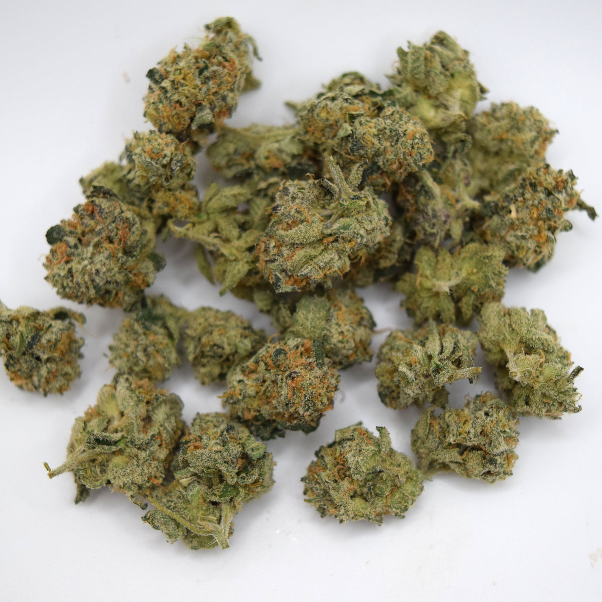 A pile of dried cannabis buds with green and orange trichome details on a plain white background.