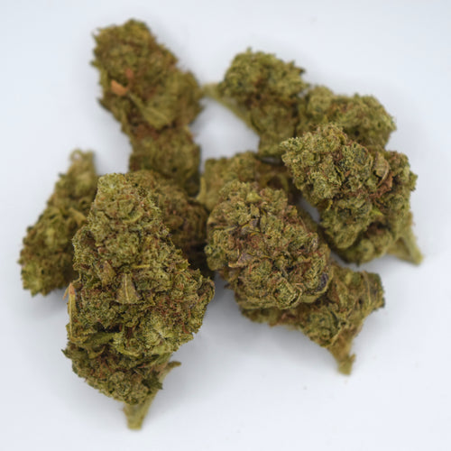 Several dried cannabis buds in olive green and brown tones, clustered together on a plain white background.