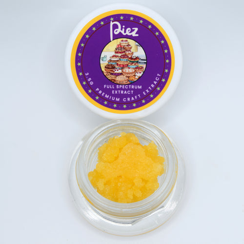 A small clear jar filled with bright yellow crystalline powder sits below its white lid, which features a purple and gold circular label reading 'Piez Full Spectrum Extract Premium Craft Extract'.