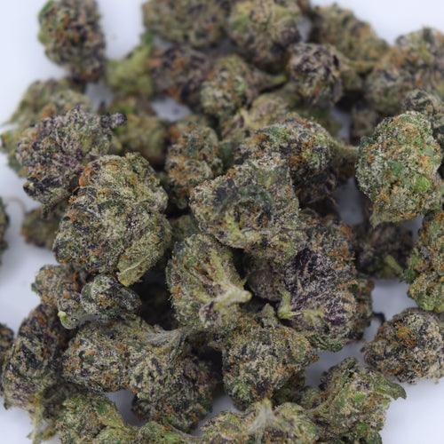A close-up pile of dried cannabis buds with green, purple, and orange tones on a white background.