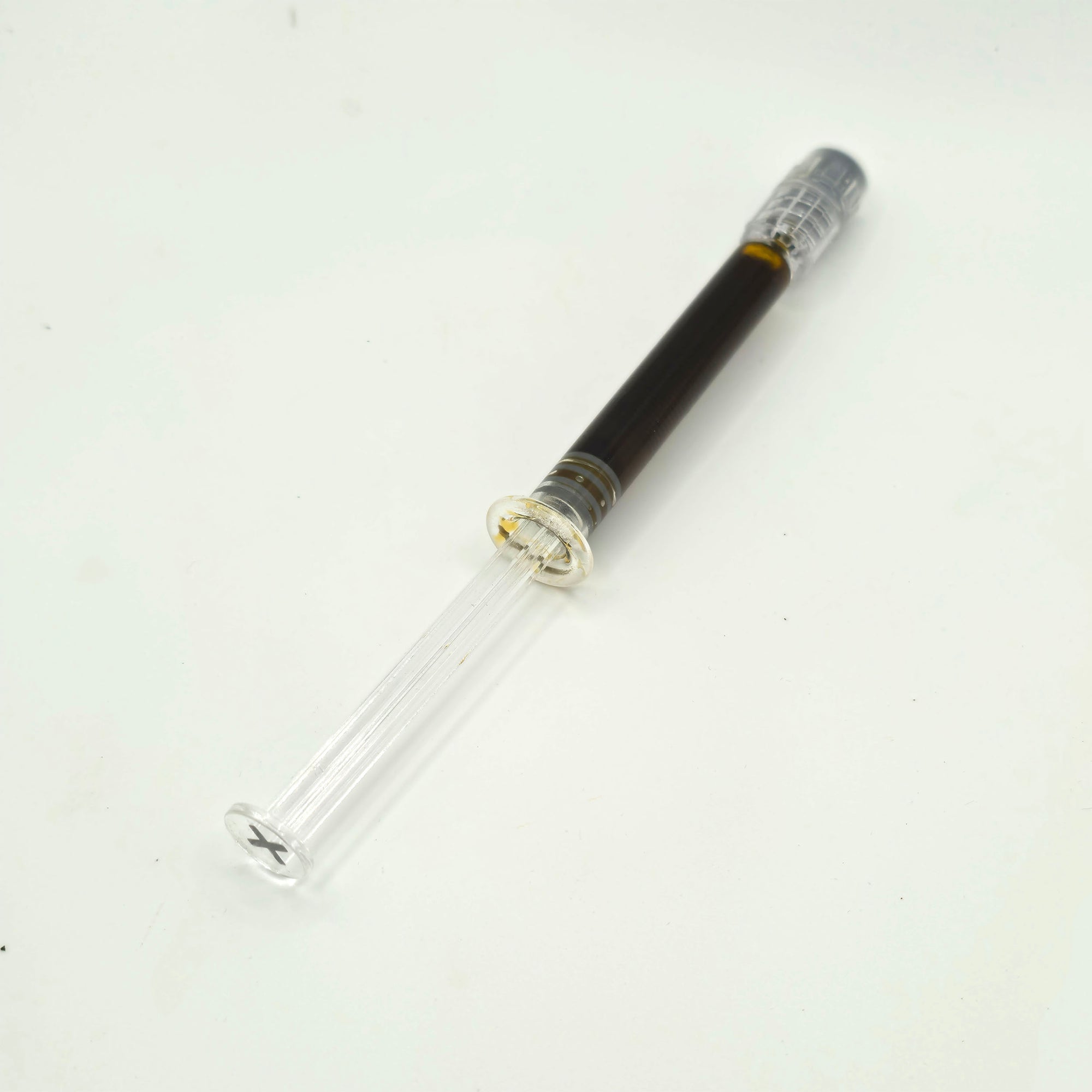 A clear glass test tube with a dark brown liquid inside and a silver screw cap, shown on a plain white background.
