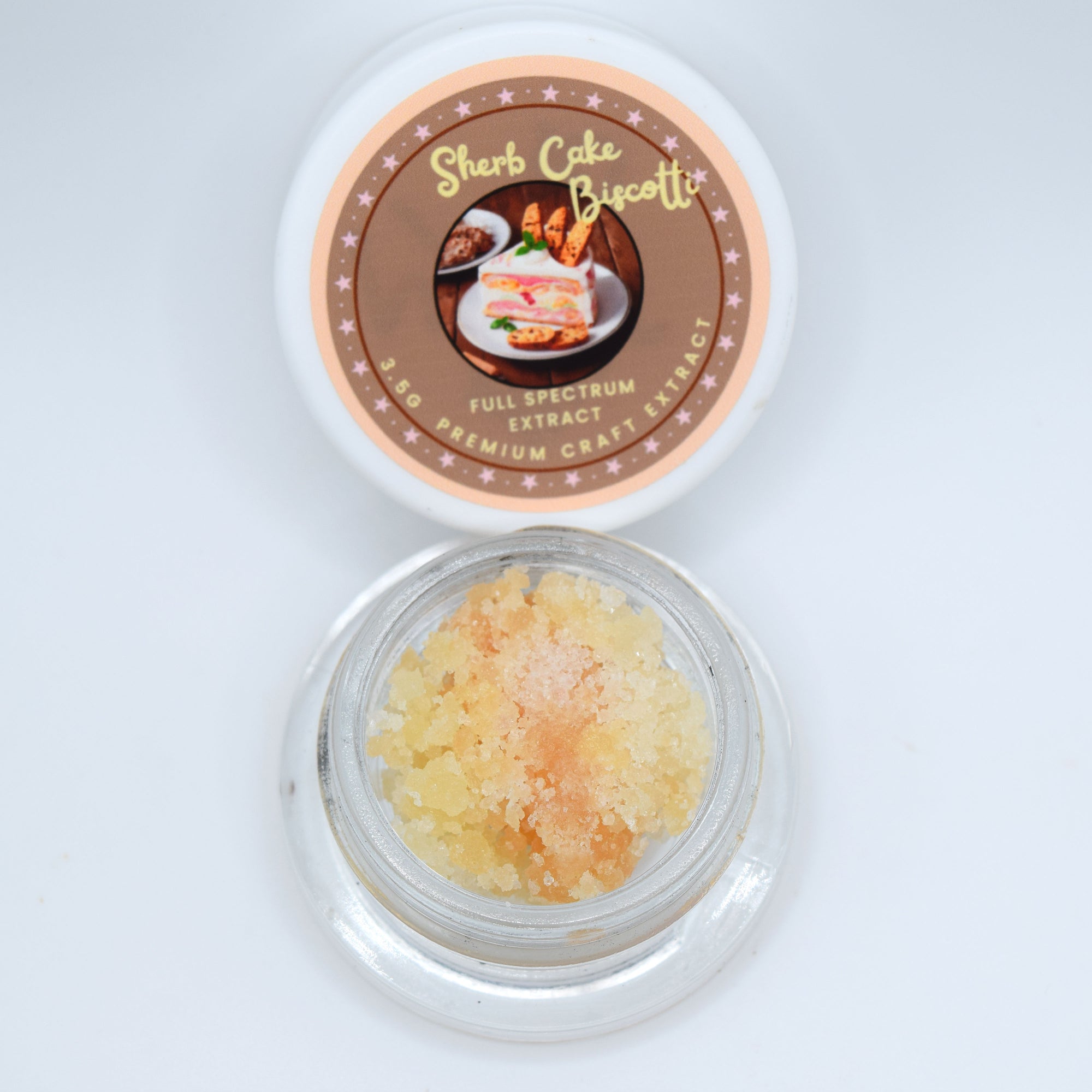An open round glass jar containing pale yellow crystalline powder, with its white lid placed above. The lid features a brown circular label reading 'Sherb Cake Biscotti' and 'Full Spectrum Craft Extract'.