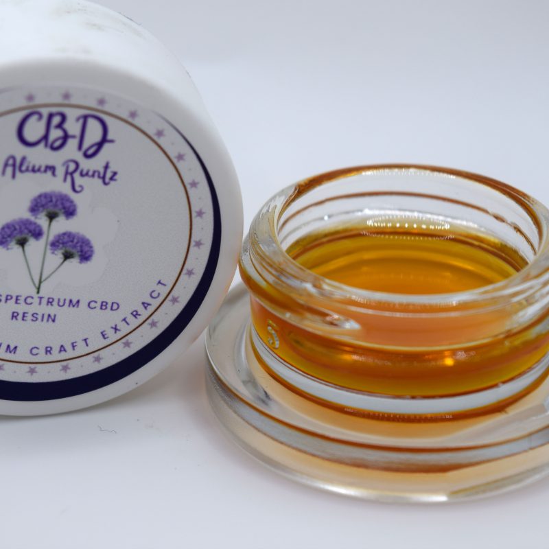 Alium Kush CBD full spectrum extract with glossy golden amber resin and a sweet fruit, savory herb, earthy Kush, spice, wood, and gassy profile.
